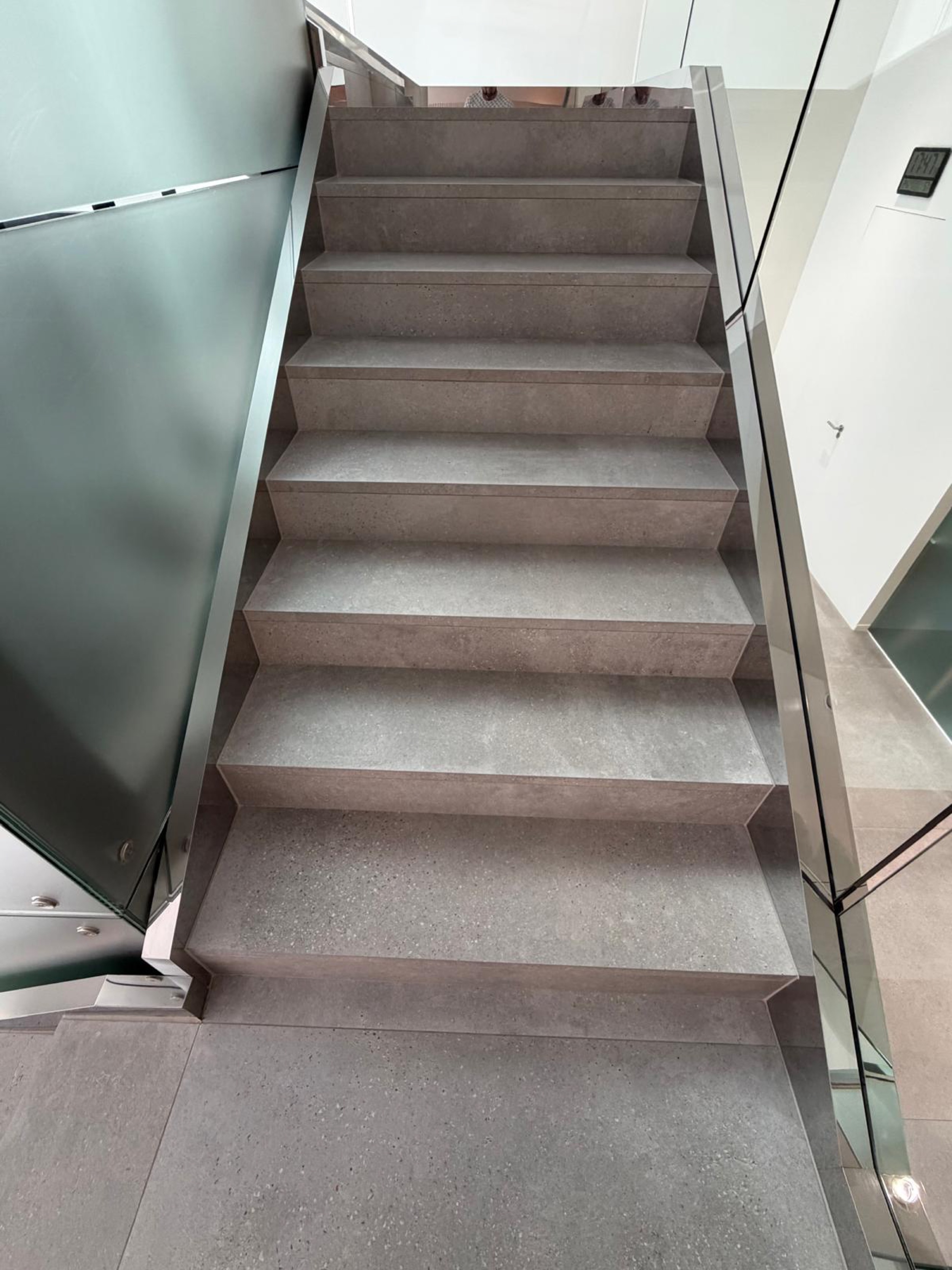 Moderne Treppe mit Glasgeländer, von oben fotografiert