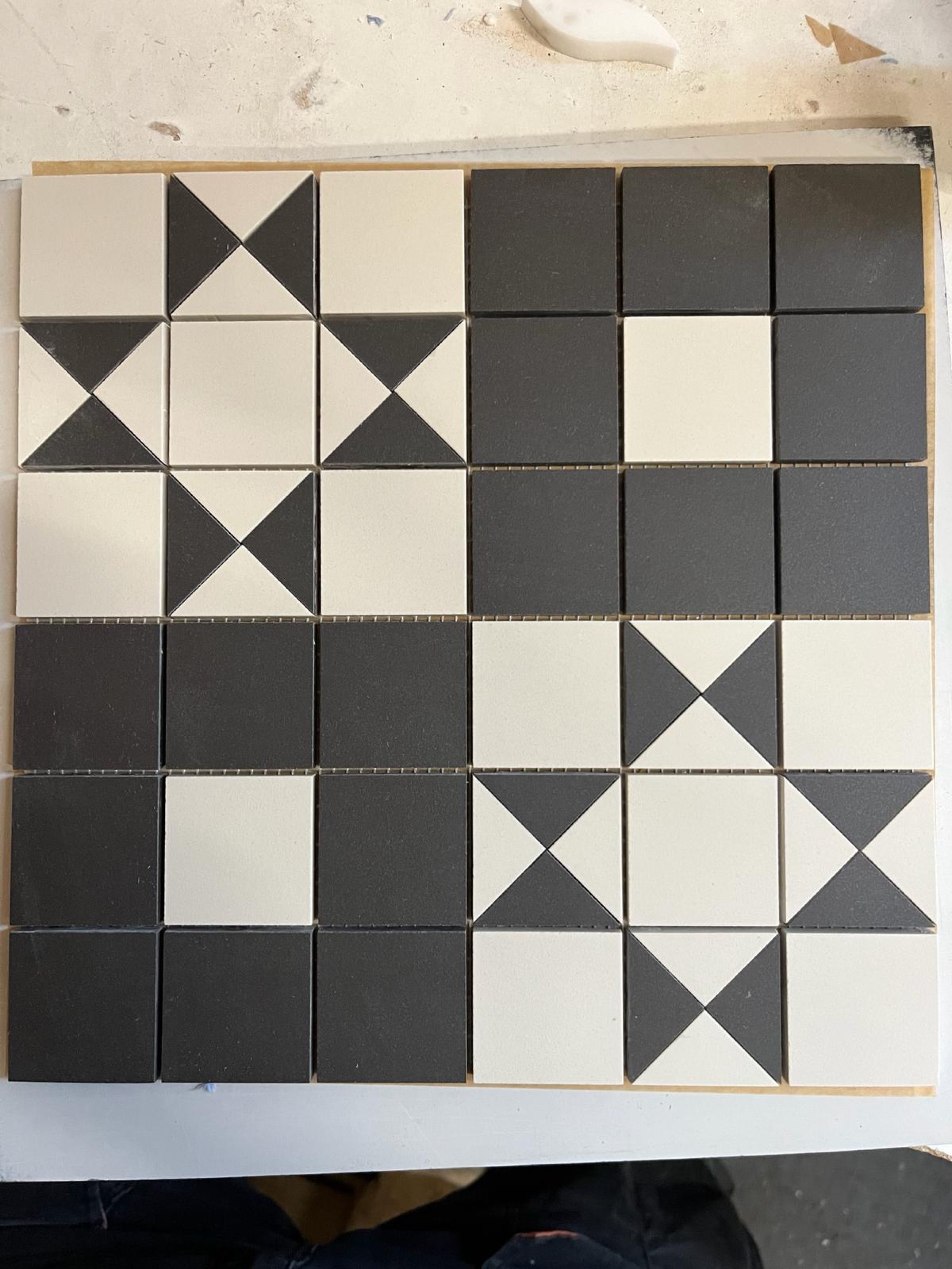 Mosaikmatte aus schwarzen und weißen Quadraten und Dreiecken im Schachbrett- und Sternmuster