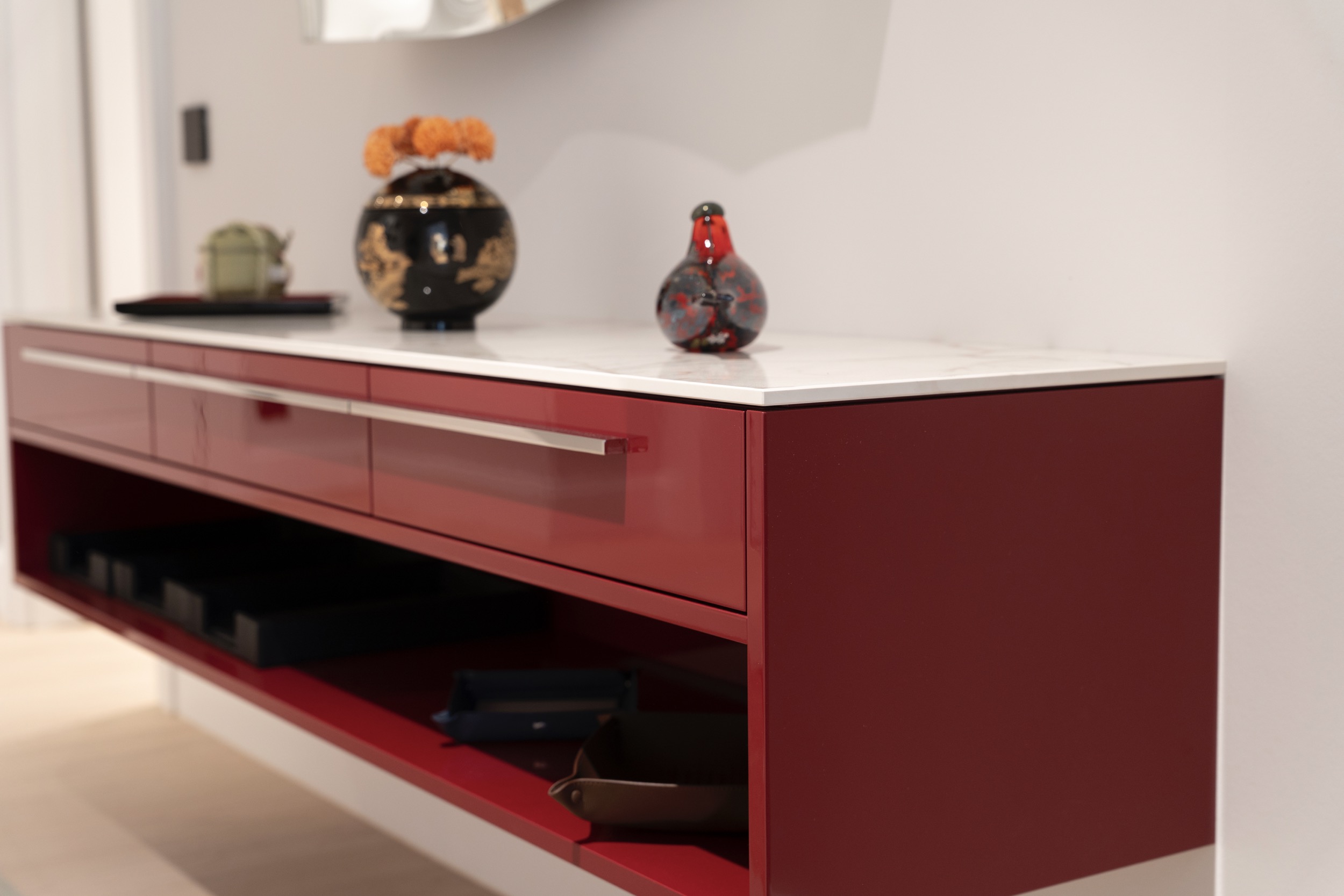 camt projekt sideboard bordeauxrot hochglanz seitenansicht weisser marmorauflage dekorvase schwarzgold glasvogel wandmontiert