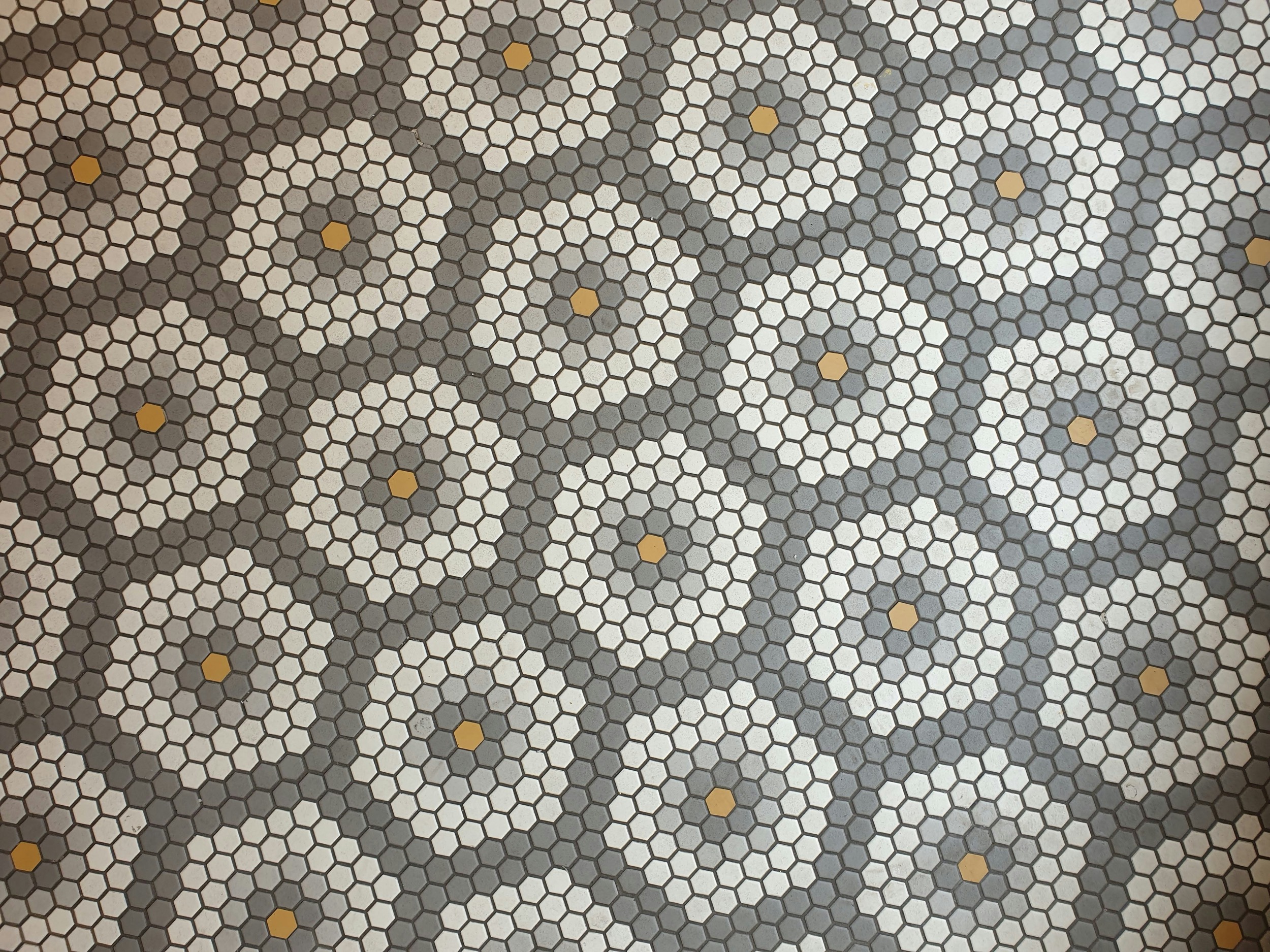 Sechseckmosaik in Grau und Weiß mit gelben Akzenten im Blumenmuster