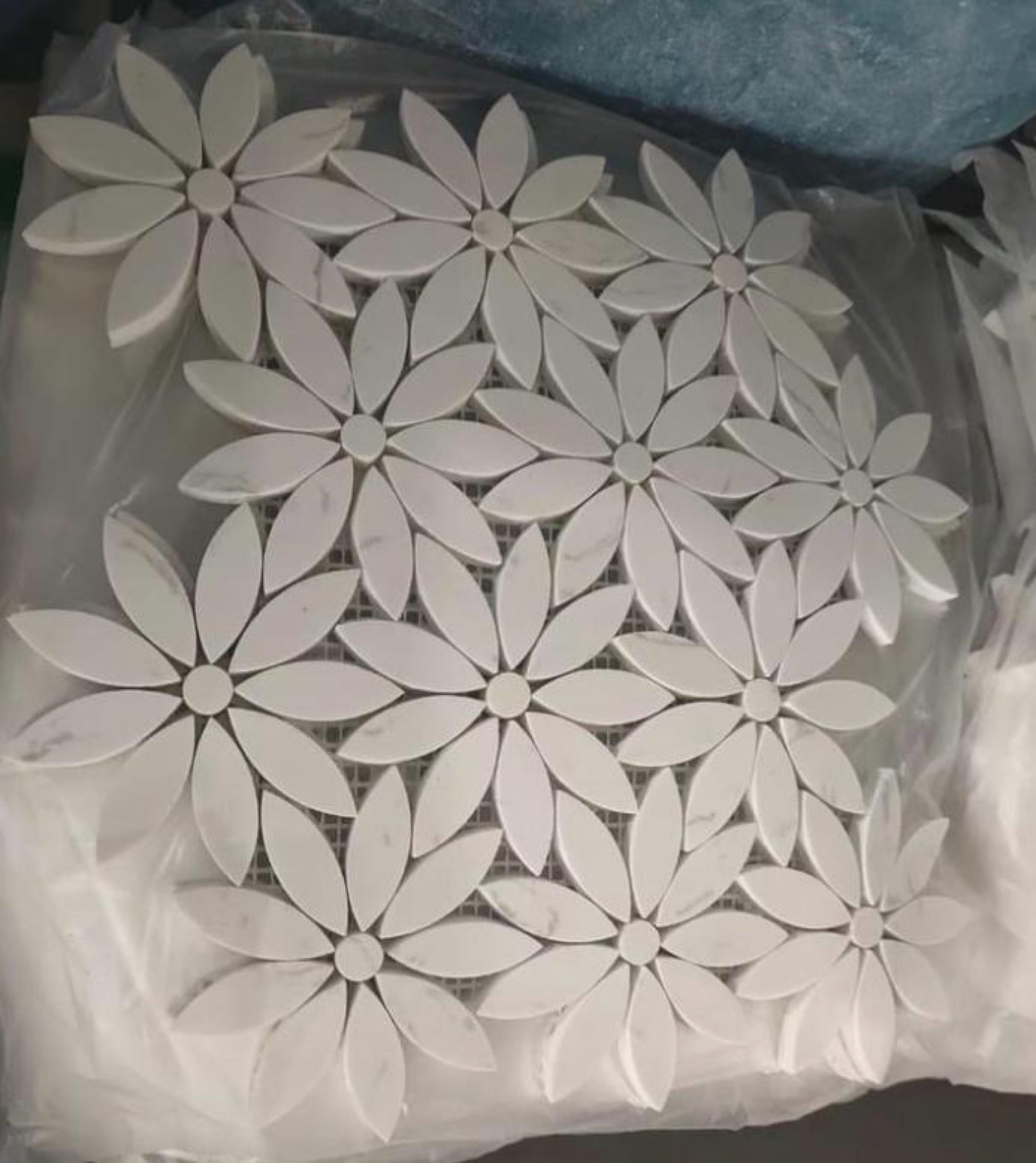 camt-steinmosaik-blumenmuster-aus-weissen-blattfoermigen-marmorstuecken-mit-runder-bluetenmitte-in-transportfolie
