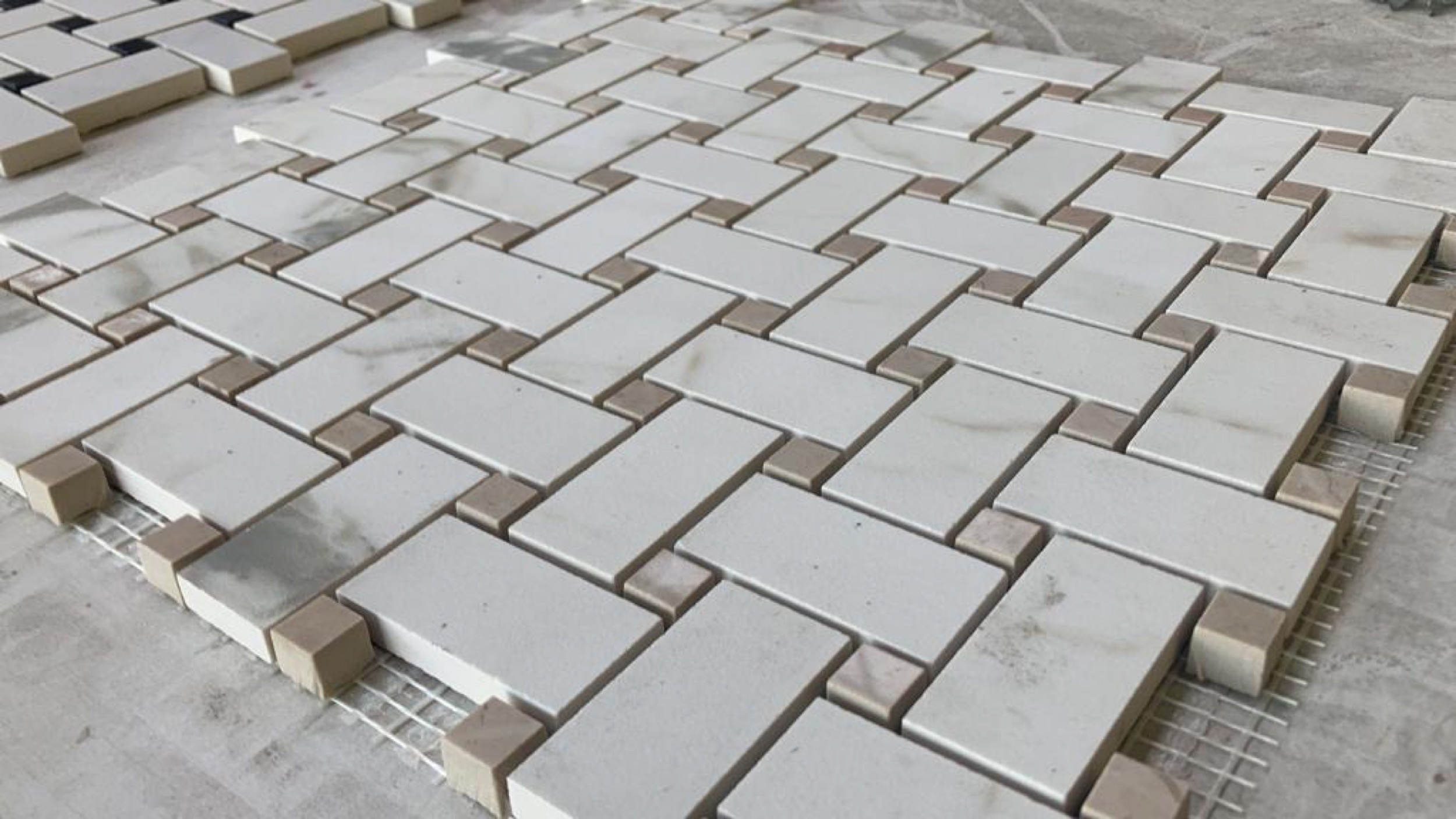 camt steinmosaik fischgraet aus weissen marmorquadern mit braunen eckchen in schraeger nahaufnahme auf werkbank