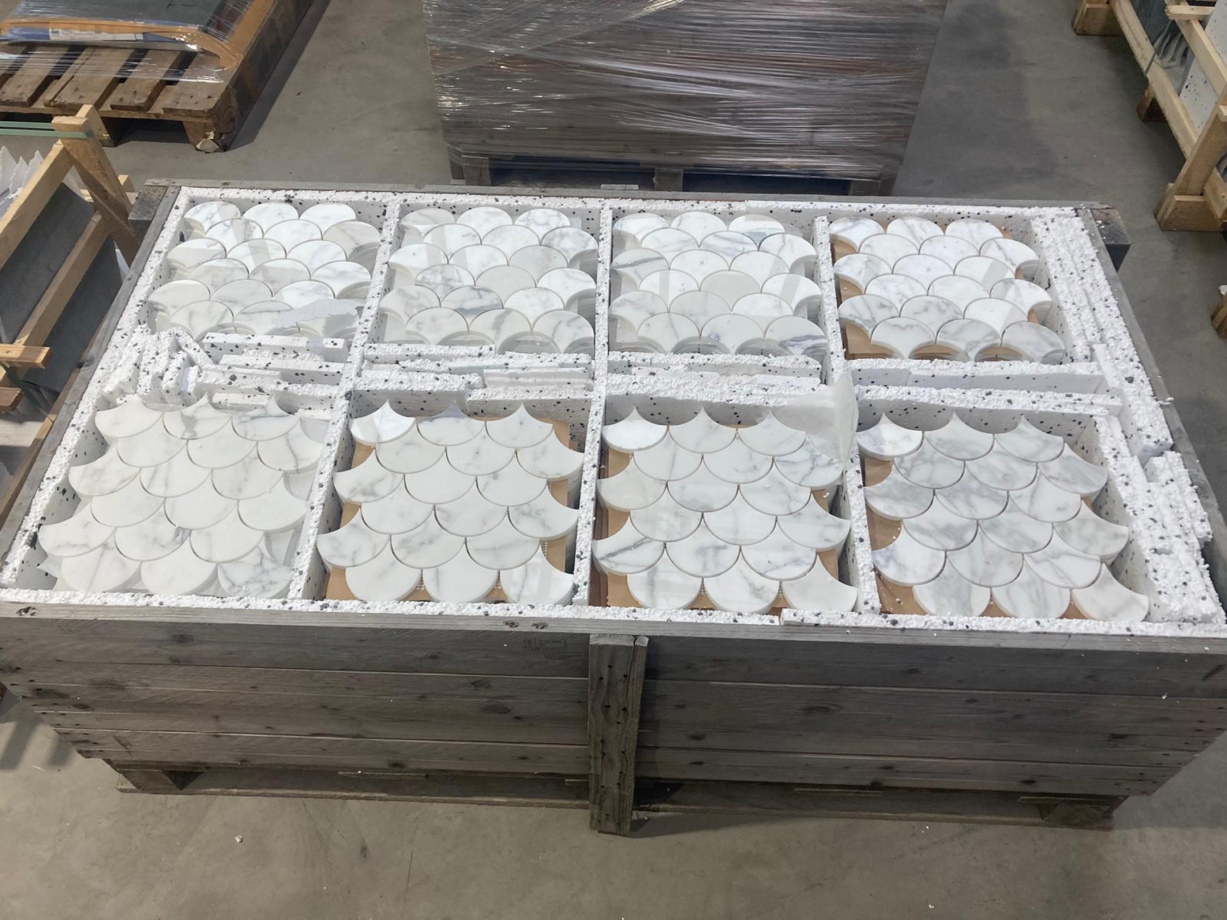 camt steinmosaik fischschuppenmuster aus weissen marmorbogen in acht mustertafeln in styropor verpackung in einer holzkiste in der lagerhalle