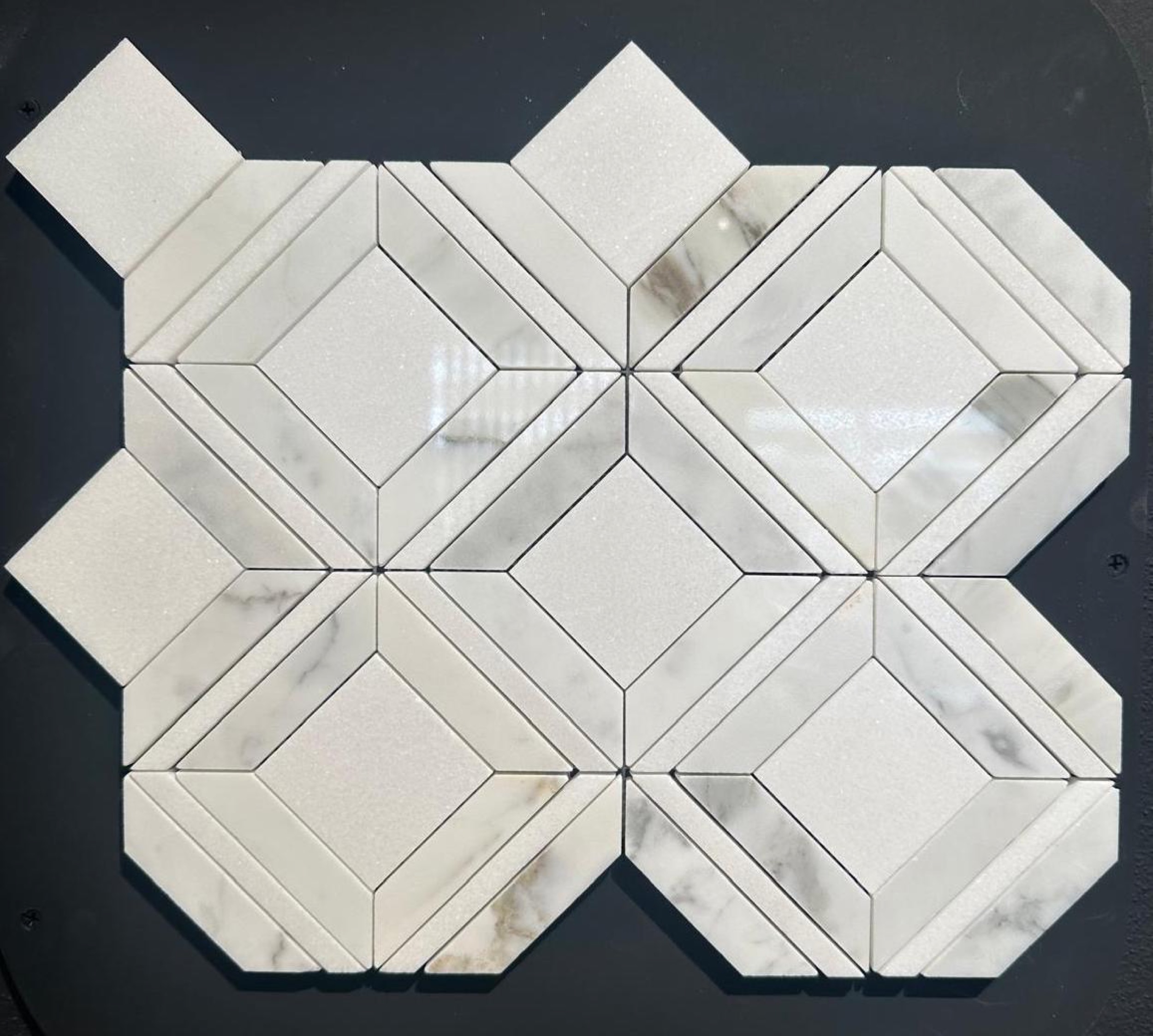 camt steinmosaik geometrisches muster aus quadraten mit rautenrahmen in weissem und grau geadertem marmor mit eckigen zuegen auf dunklem hintergrund